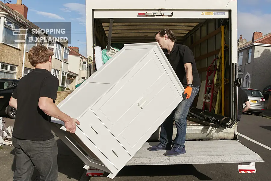 Removals business. Two men lifting a wardrobe onto the removals van.